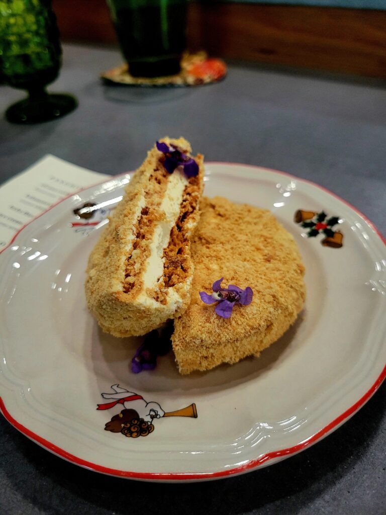 Silvanas cookie with two small purple flowers on top of a plate.